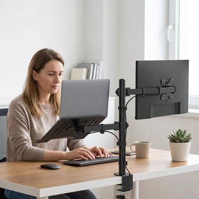 Bras d'écran Femme travaillant à un bureau avec ordinateur portable et écran installés sur un support double réglable