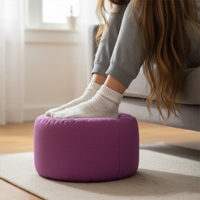 Pouf​ repose pied Pieds en chaussettes reposant sur un pouf rond violet en tissu, utilisé comme repose-pieds dans un salon lumineux