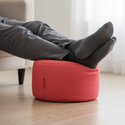 Pouf​ repose pied Pieds reposant sur un pouf rond rouge en tissu, utilisé comme repose-pieds dans un salon lumineux.