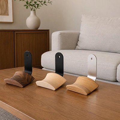 Support casque​ Trois supports muraux pour casque audio en bois et métal, présentés en différentes finitions sur une table