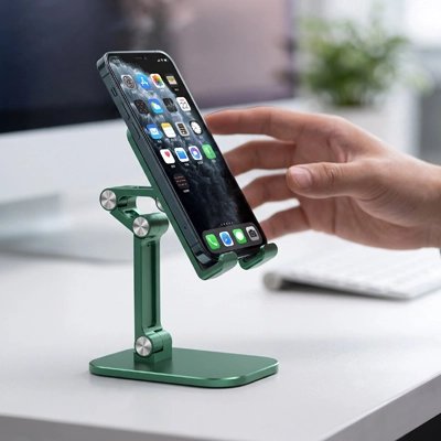 Support pour tablette Main utilisant un smartphone posé sur un support de bureau vert réglable et articulé, devant un écran d’ordinateur