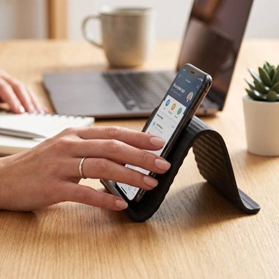 Support telephone femme toichant téléphone sur support sur bureau travail