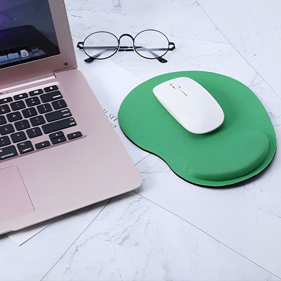 Tapis de souris repose poignée Souris blanche posée sur un tapis de souris ergonomique vert avec repose-poignet, à côté d’un ordinateur portable